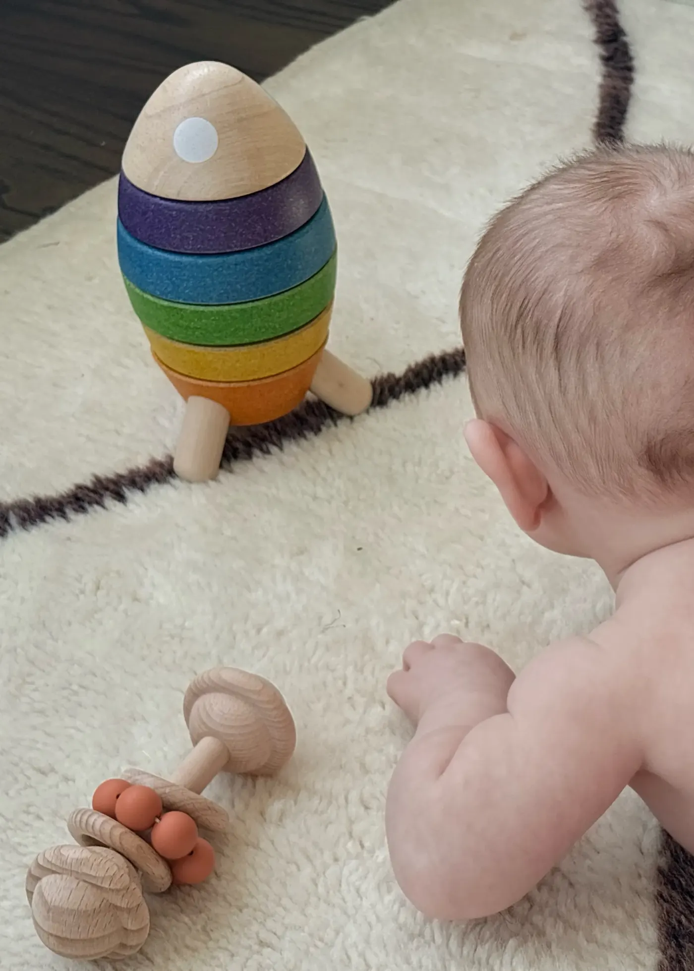 Baby with wooden stacking toy and rattles